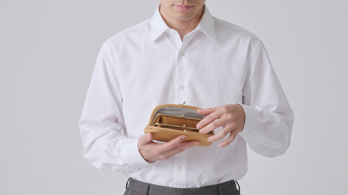 ブラックのがま口ウォレットを持つ男性