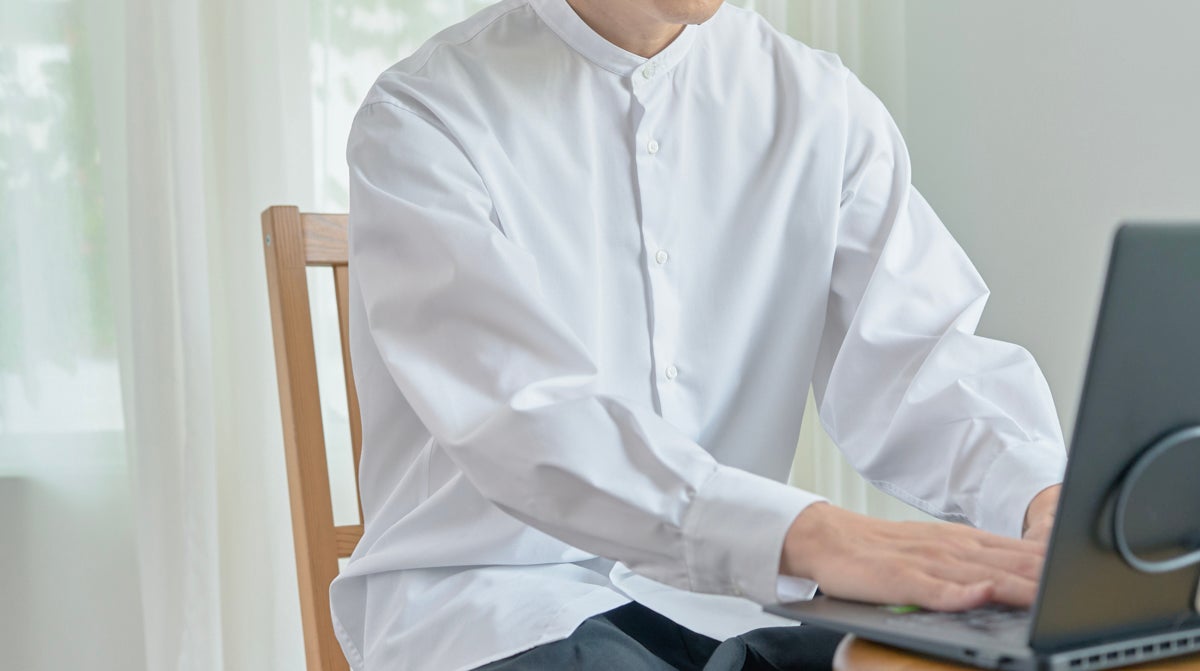 デスクワークで白いスタンドカラーシャツを着る男性
