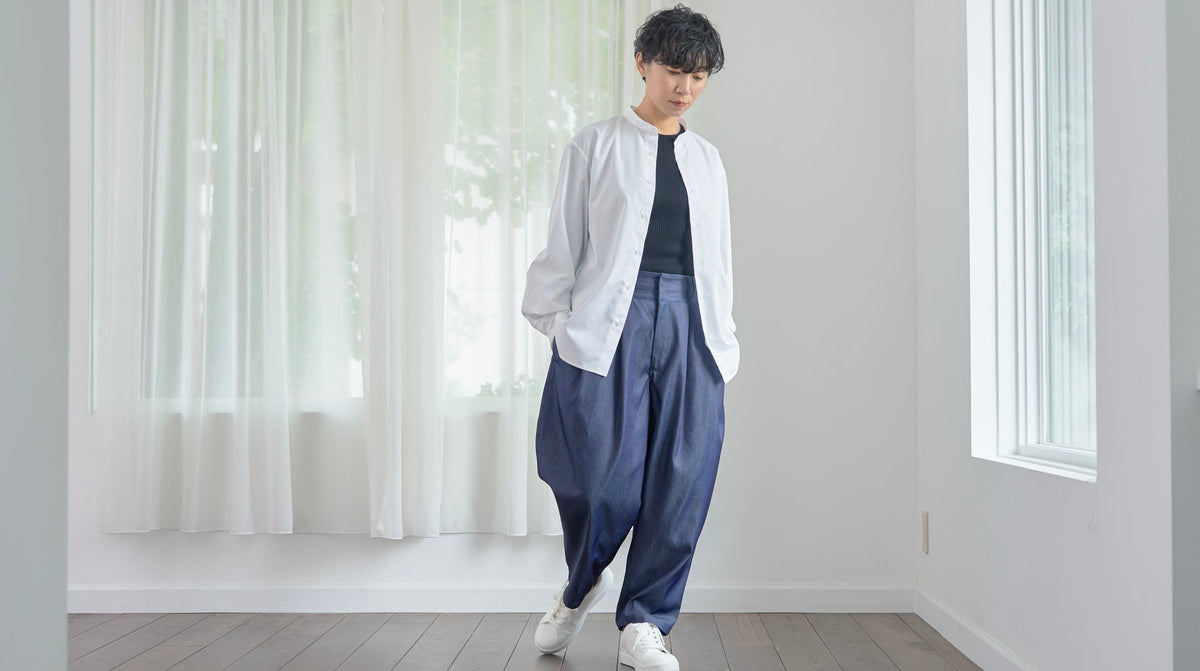 白いスタンドカラーシャツを羽織った女性
