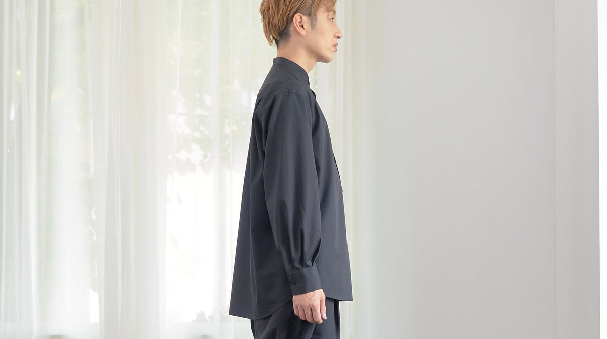 黒いスタンドカラーシャツを着た男性の横姿